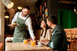 © BGStock72 - Waiter serves delicious vegetarian dishes to cheerful diners in a vibrant café during a sunny afternoon