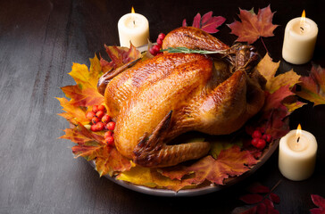 Thanksgiving day dinner with roasted turkey, leaves and candles