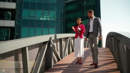 Wall Mural - Group of diverse professional colleagues talking walking  cross bridge, happy friendly indian female and caucasian male coworker having conversation discuss project going along business area