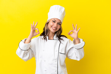 Young Russian chef girl isolated on yellow background showing an ok sign with fingers