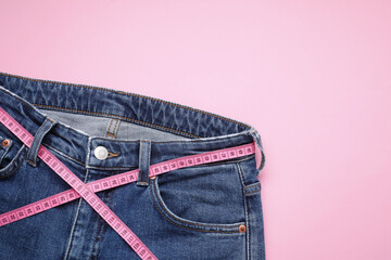 Poster - Jeans and measuring tape on pink background, top view. Space for text