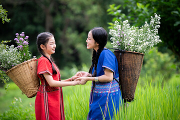 woman carries a large, woven basket on her back filled with white and purple flowers collected from the area nnection with nature, as well as the warmth of a beautiful, natural environment.