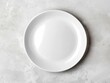 © WE.ARE.AI - Top-view of a white ceramic plate on a light concrete surface, creating a clean, industrial look for product presentations