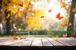 © Super Stocks - A wooden table with an autumn background, featuring colorful leaves and sunlight in the sky. The focus is on the empty space of the tabletop for product display or presentation.