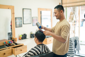 In a bustling barber shop, a man is skillfully cutting the hair of another man, demonstrating the artistry and precision of hair styling