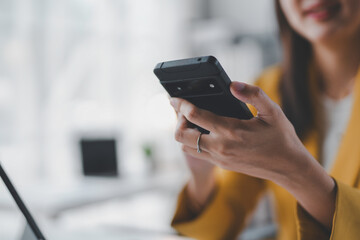 Close up view of a businesswoman holding a smartphone in an office, concept of mobile technology and communication