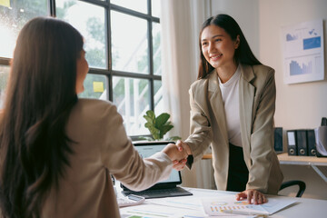 Two asian businesswomen are shaking hands after reaching an agreement during a business meeting