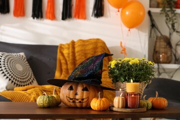 Wall Mural - Burning candles, flowers and pumpkins on table in room decorated for Halloween