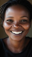 A joyful African woman smiles brightly, showcasing her natural beauty and happiness