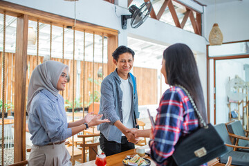 new friends meeting, two asian women meet a man in a coffee shop