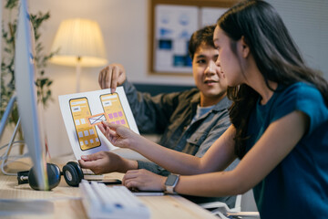 Poster - Two asian ui/ux designers collaborating in the office, analyzing and discussing a mobile app interface design, showcasing teamwork and dedication for their startup