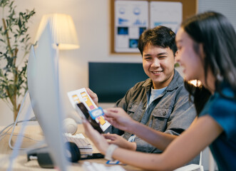 Poster - Two young ui/ux designers are working together in the office, discussing mobile app interface design during a meeting. They are smiling and looking at a smartphone