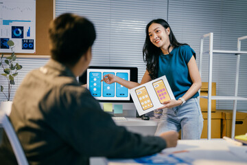 Poster - Two asian ui/ux designers are working on a new mobile app interface in their office, pointing at screens and discussing