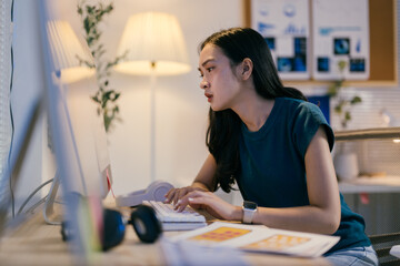Aufkleber - Young professional is concentrating on her work late at night, diligently typing on her computer keyboard with a focused expression