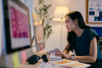 Poster - Young woman designer works late at night in her home office, focused on meeting a deadline for her project. She types on her computer, determined and motivated
