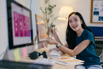 Poster - Ui designer is using sticky notes while working on a mobile application in her office. She is smiling and looking happy with her work