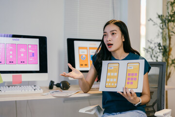 Poster - Web designer is showing mobile application mockups while leading a design meeting in an office. She is gesturing with her hand as she explains the new user interface