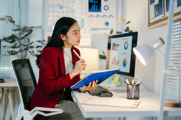 Poster - Determined businesswoman working late, analyzing financial data and exploring new opportunities at her office desk with a laptop