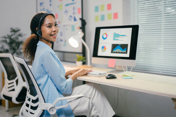 Poster - african american businesswoman is working late in the office, focused on her computer screen and wea
