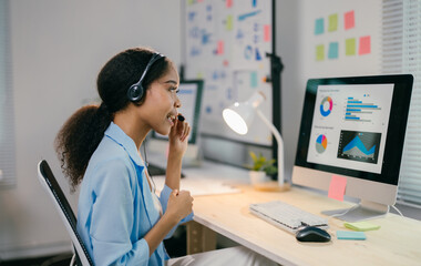 Smiling woman in a modern office, using a laptop for a video call. Surrounded by charts, she represents remote work in the digital age