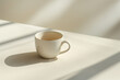 © Urszula - Single coffee cup on plain white table with soft lighting