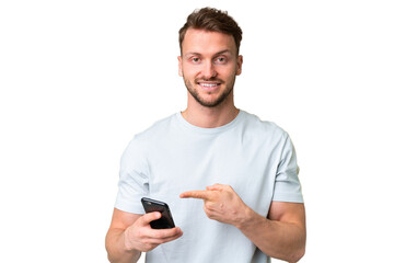 young handsome caucasian man over isolated chroma key background using mobile phone and pointing it