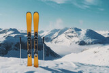 Fototapeta Góry - Pair of yellow skis and poles are standing in snow on mountain top. Outdoor adventure activities in winter season