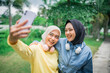 © Odua Images - Two close friends happily enjoying taking a selfie together in a beautiful green outdoor park