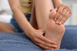© New Africa - Woman suffering from foot pain on bed at home, closeup