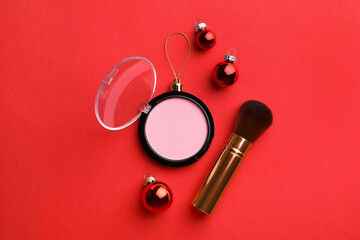 Wall Mural - Blusher in shape of Christmas ball and brush on red background, flat lay