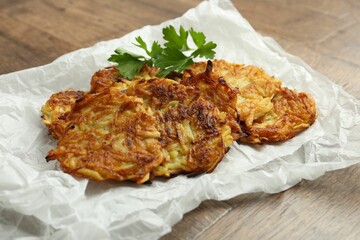 Delicious potato pancakes and parsley on wooden table, closeup