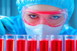 © ChaoticDesignStudio - A scientist in protective gear analyzes red liquids in test tubes during a laboratory experiment