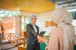 © Odua Images - Two professional women engaging in a formal handshake within a contemporary office environment