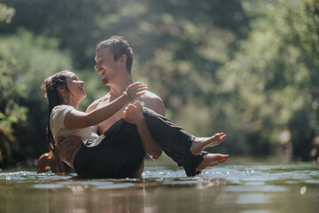 Poster - Happy couple enjoying a playful moment in a river, surrounded by lush greenery and sunlight. Captures joy, love, and nature in a beautiful setting.