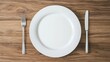 © sunchai - Empty plate with fork and knife, wood background