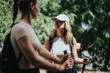 © qunica.com - Two women smiling and talking while hiking in nature, carrying trekking poles and backpacks, enjoying the outdoor adventure.