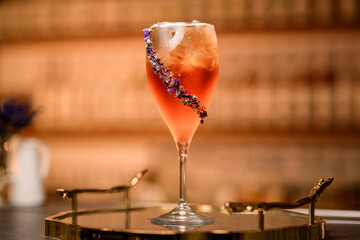 Glass with a cold cocktail with ice, the outside of which is decorated with flowers