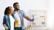 © Prostock-studio - Happy Black Couple Standing In Fresh-Cleaned Living Room And Looking Aside, Satisfied After Successful Tidying, Copy Space