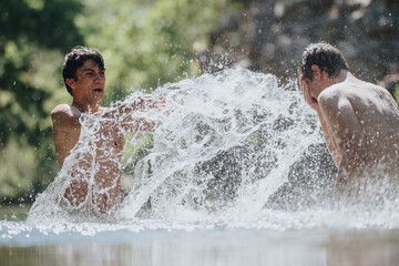 Wall Mural - Two young men laughing and splashing in a clear stream, capturing the joy of summer and outdoor fun. Vibrant and carefree, this image radiates energy and youthfulness.