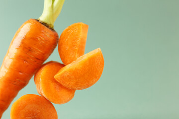 Wall Mural - Whole and cut fresh carrots on green background, closeup. Space for text