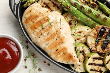 Delicious grilled vegetables with chicken breast in baking dish and sauce on white wooden table, flat lay