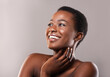 African beauty. Portrait of happy beautiful black woman touching her soft skin and looking upwards at copy space on grey background