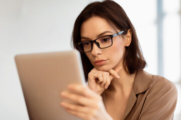 Aufkleber - Internet Surfing. Close up portrait of beautiful pensive girl in specs working on digital tablet