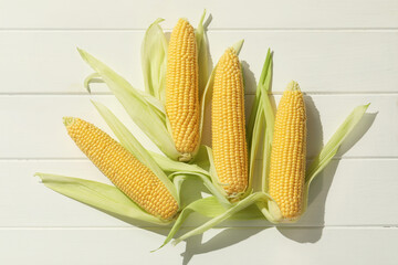 Wall Mural - Many fresh ripe corncobs with green husks on white wooden table, top view