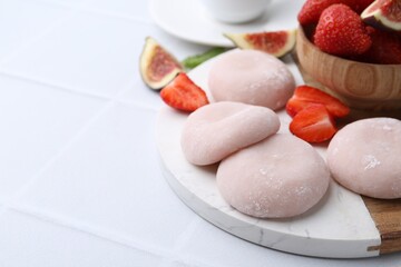 Canvas Print - Delicious mochi, strawberries and fig on white tiled table, closeup. Space for text