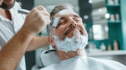 A mature man enjoys a relaxing shave at a barber shop, displayed with soothing shaving cream application on his face, capturing a moment of luxurious self-care.