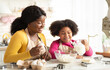 © Prostock-studio - Cheerful Black Family Mother And Daughter Baking Together In Kitchen. Cute Little African American Girl Adding Ingregients To Bowl While Preparring Dough For Cookies With Mom At Home, Free Space
