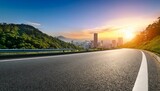 asphalt highway road and green mountain with city skyline at sunset