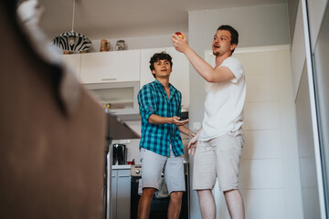 Wall Mural - Two young men having fun in a modern kitchen, casually interacting in a relaxed and playful manner. The scene captures a sense of friendship and leisure in a contemporary home environment.