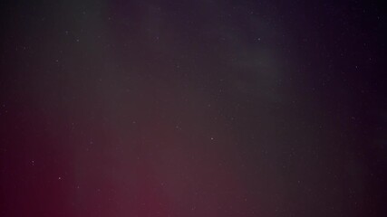 Wall Mural - time lapse of red and green aurora dancing in a star filled sky with thin clouds